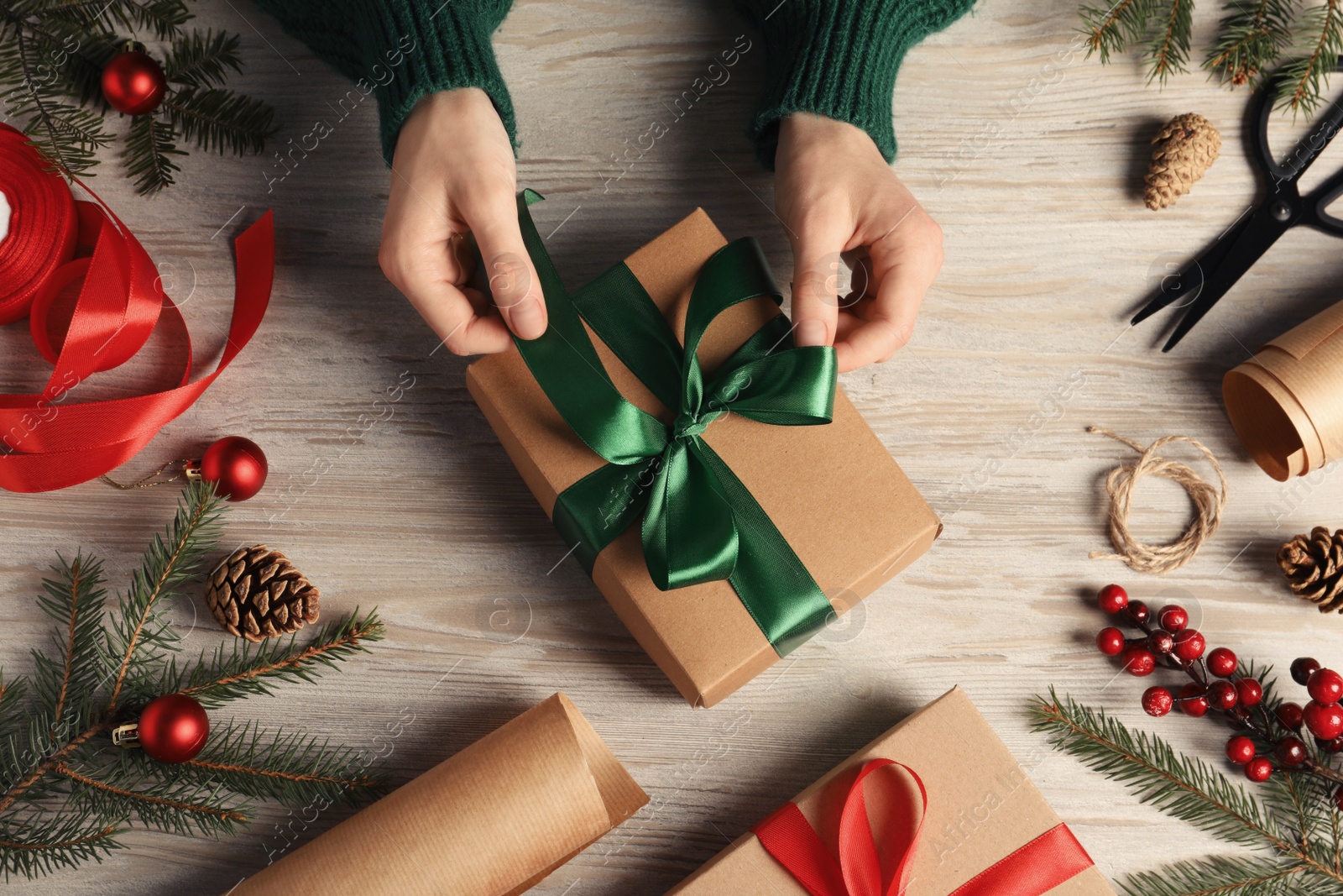 Photo of Woman decorating gift box at white wooden table, top view. Christmas present