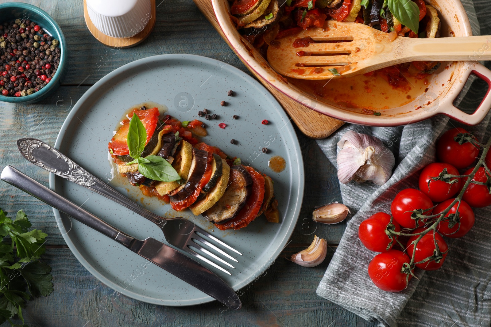 Photo of Delicious ratatouille served with basil on grey wooden table, flat lay