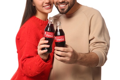 Photo of MYKOLAIV, UKRAINE - JANUARY 27, 2021: Young couple holding bottles of Coca-Cola against white background, closeup