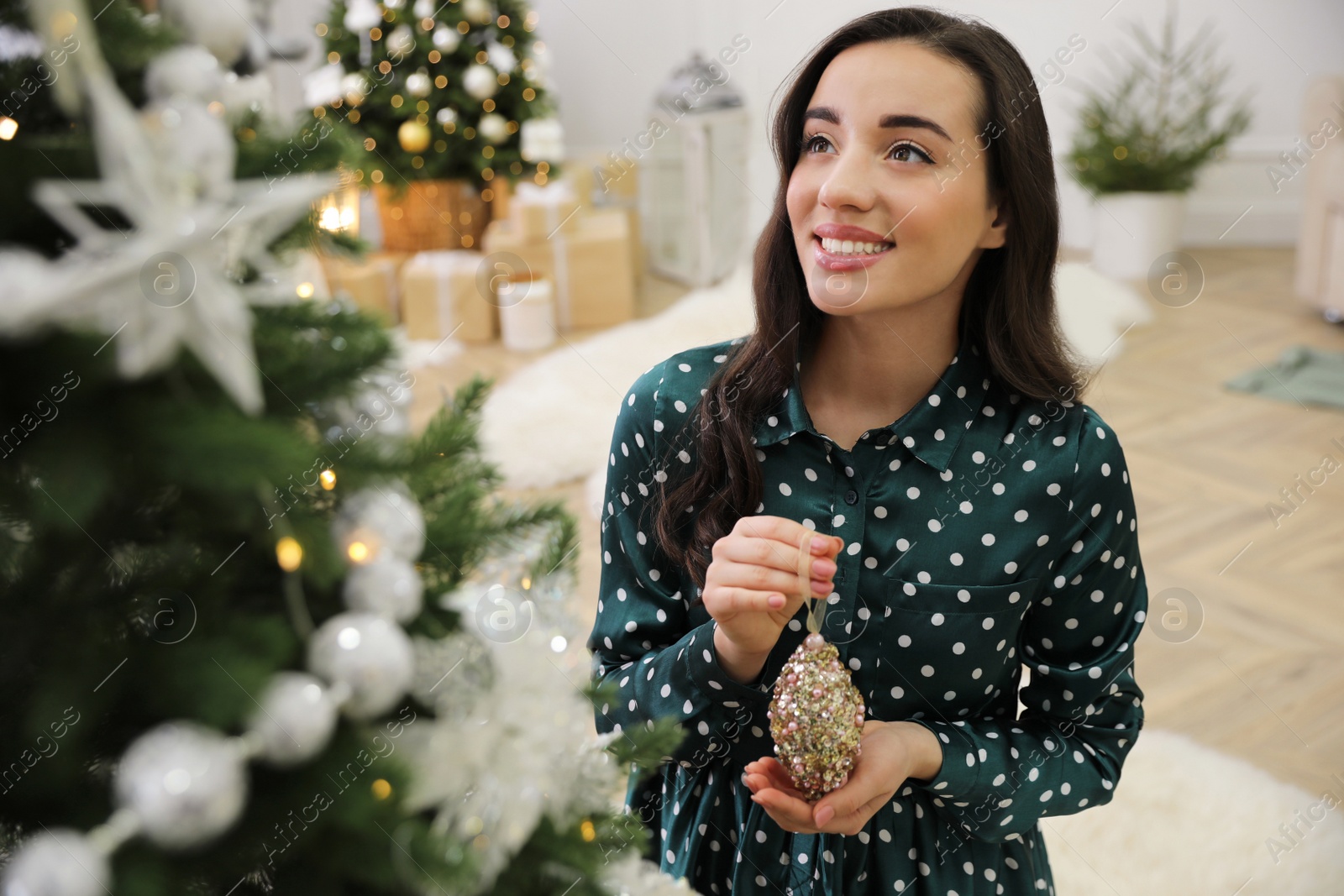 Photo of Young woman decorating Christmas tree at home