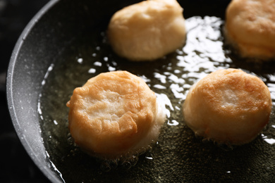 Photo of Cooking delicious donuts in hot oil, closeup