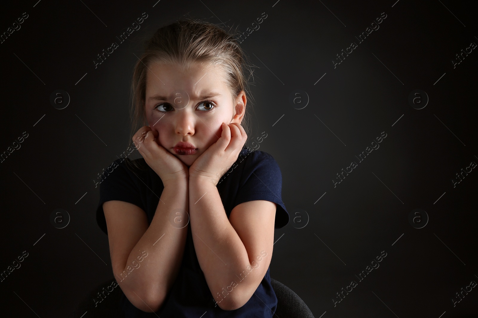 Photo of Little girl with bruises on face against dark background, space for text. Domestic violence victim