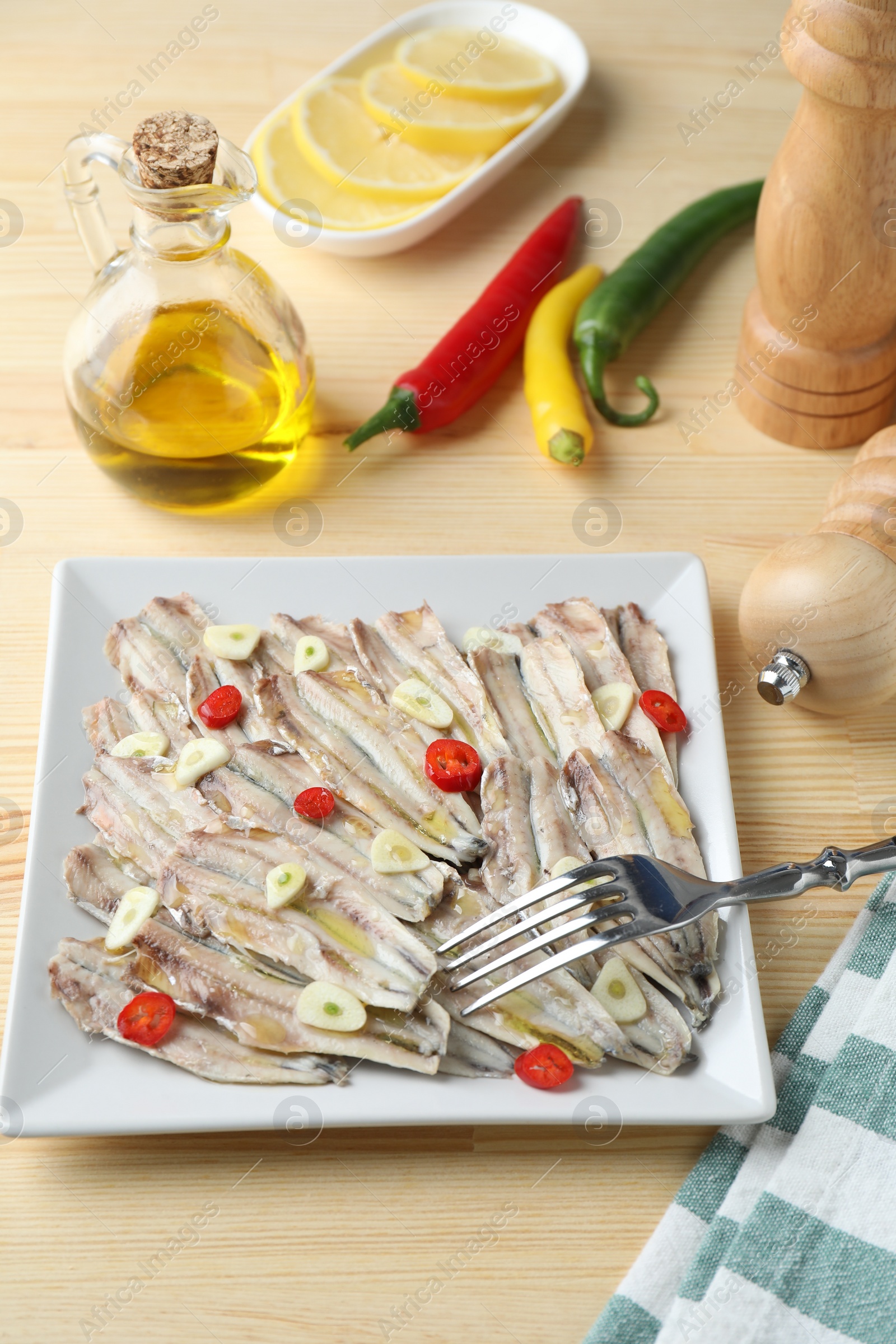 Photo of Tasty pickled anchovies served on wooden table