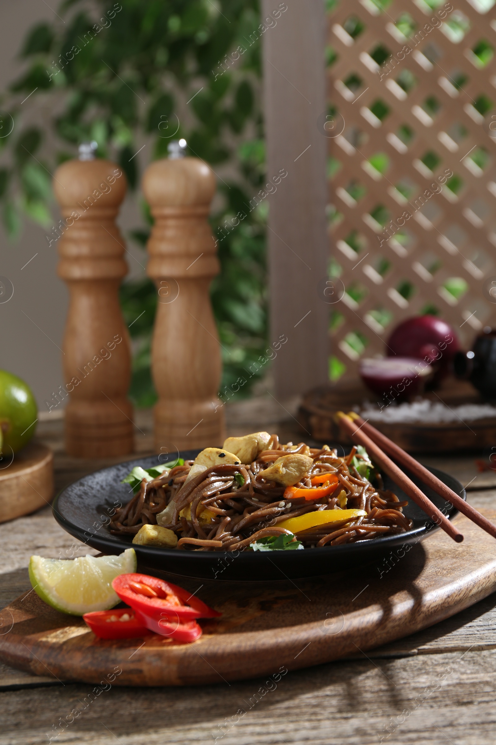 Photo of Stir-fry. Tasty noodles with meat and vegetables served on wooden table