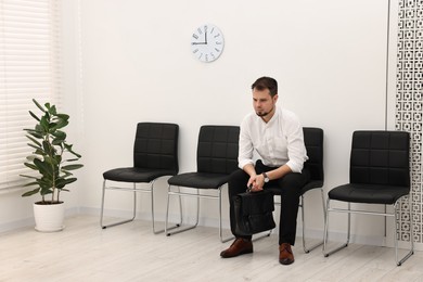 Photo of Man sitting on chair and waiting for job interview indoors