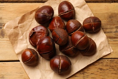 Photo of Fresh edible sweet chestnuts on wooden table, top view