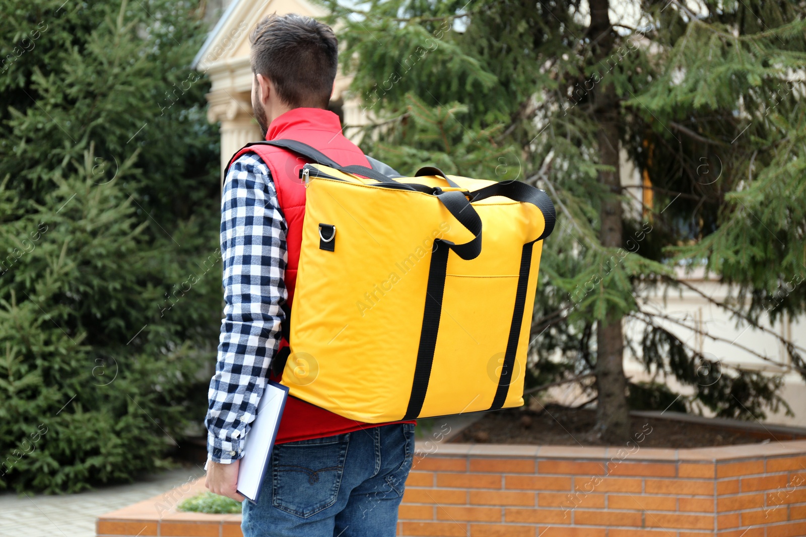 Photo of Courier with thermo bag and clipboard on city street. Food delivery service