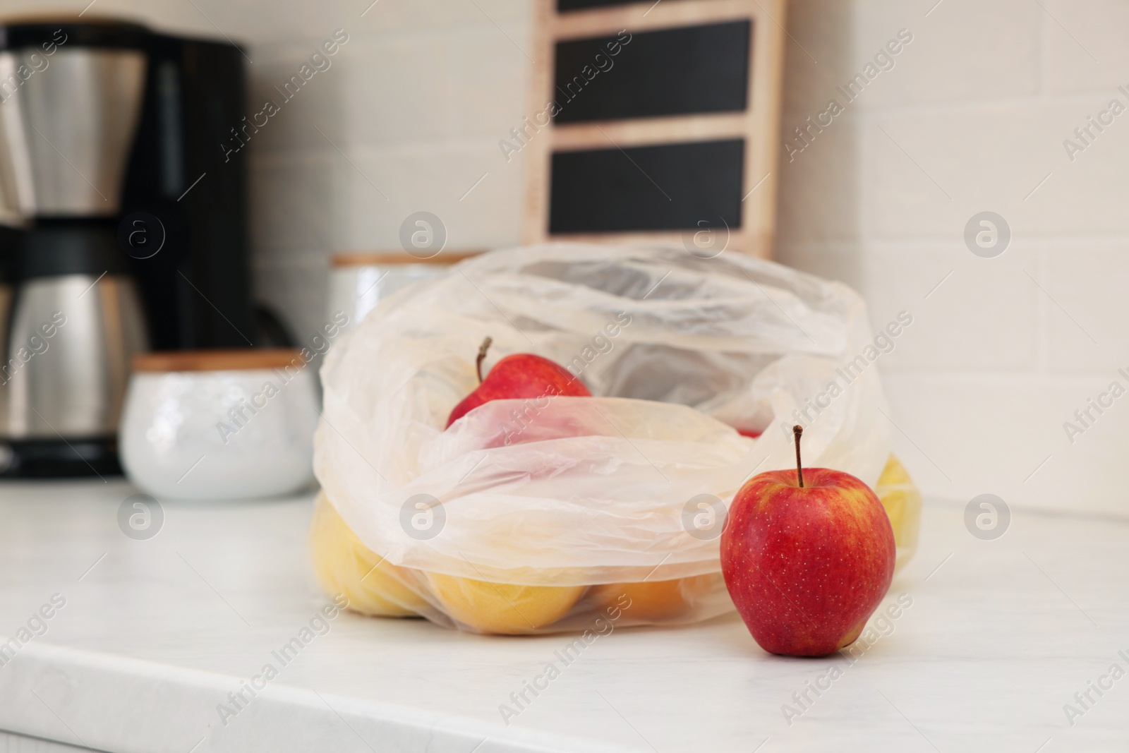 Photo of Plastic bags with different fresh products on white countertop in kitchen