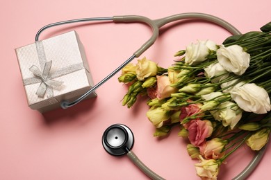 Stethoscope, gift box and flowers on pink background, flat lay. Happy Doctor's Day