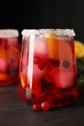 Photo of Tasty cranberry cocktail with ice cubes in glass on dark gray table