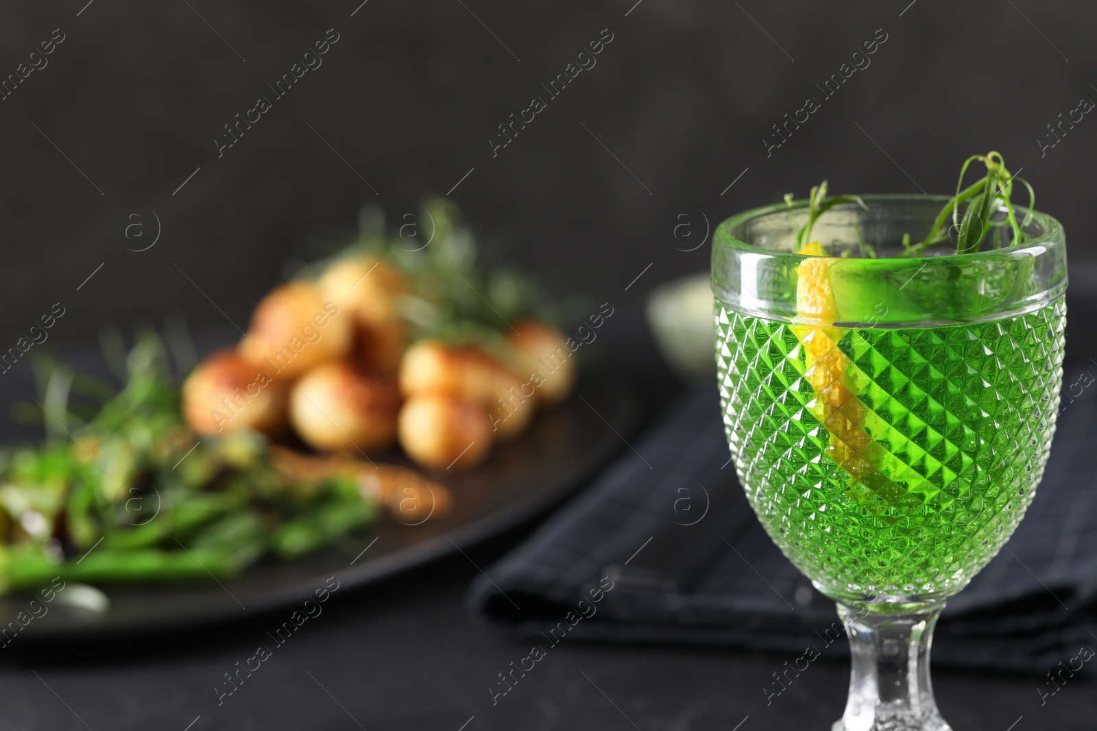 Photo of Delicious drink with tarragon in glass on dark table, closeup. Space for text