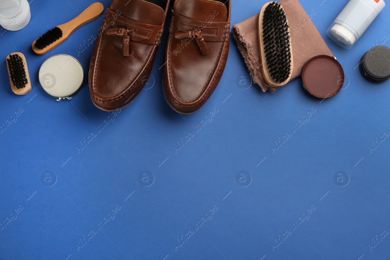 Photo of Flat lay composition with shoe care accessories and footwear on blue background. Space for text