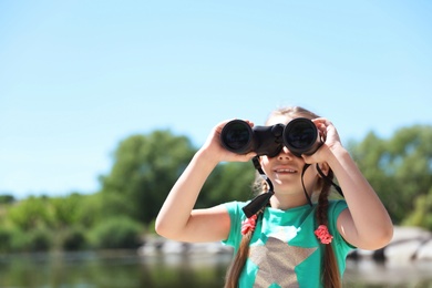 Photo of Little girl with binoculars outdoors. Summer camp