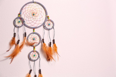 Photo of Beautiful handmade dream catcher on beige wall. Space for text