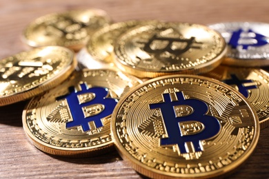 Shiny bitcoins on wooden background, closeup view. Digital currency