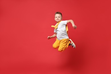 Photo of Happy little boy dancing on red background. Space for text