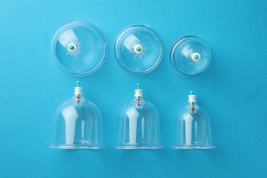 Photo of Plastic cups on light blue background, flat lay. Cupping therapy
