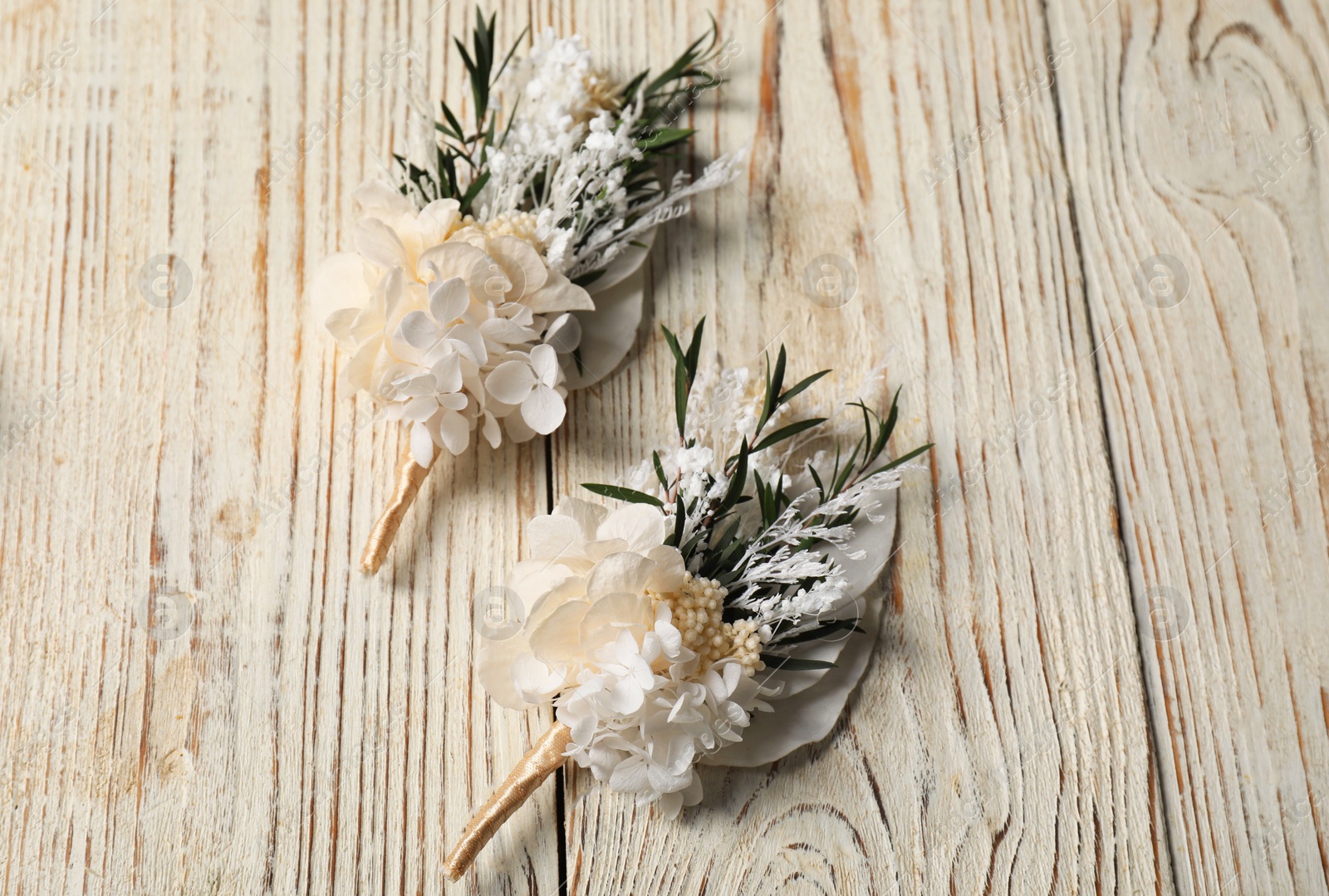 Photo of Stylish boutonnieres on light wooden table, top view