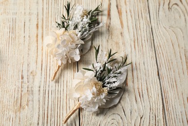 Photo of Stylish boutonnieres on light wooden table, top view