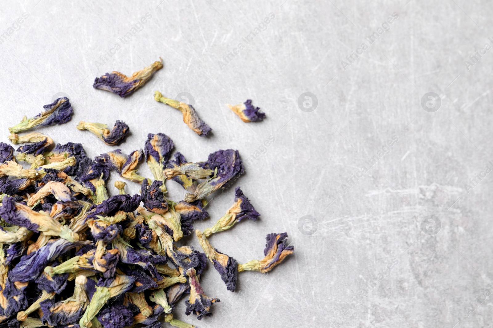 Photo of Pile of dry organic blue Anchan on light table, flat lay with space for text. Herbal tea