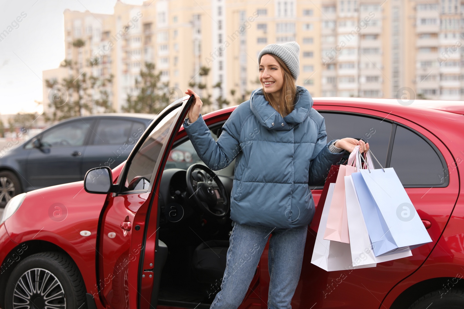 Photo of Woman with shopping bags near her car outdoors