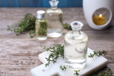 Photo of Thyme essential oil and fresh plant on wooden table, space for text