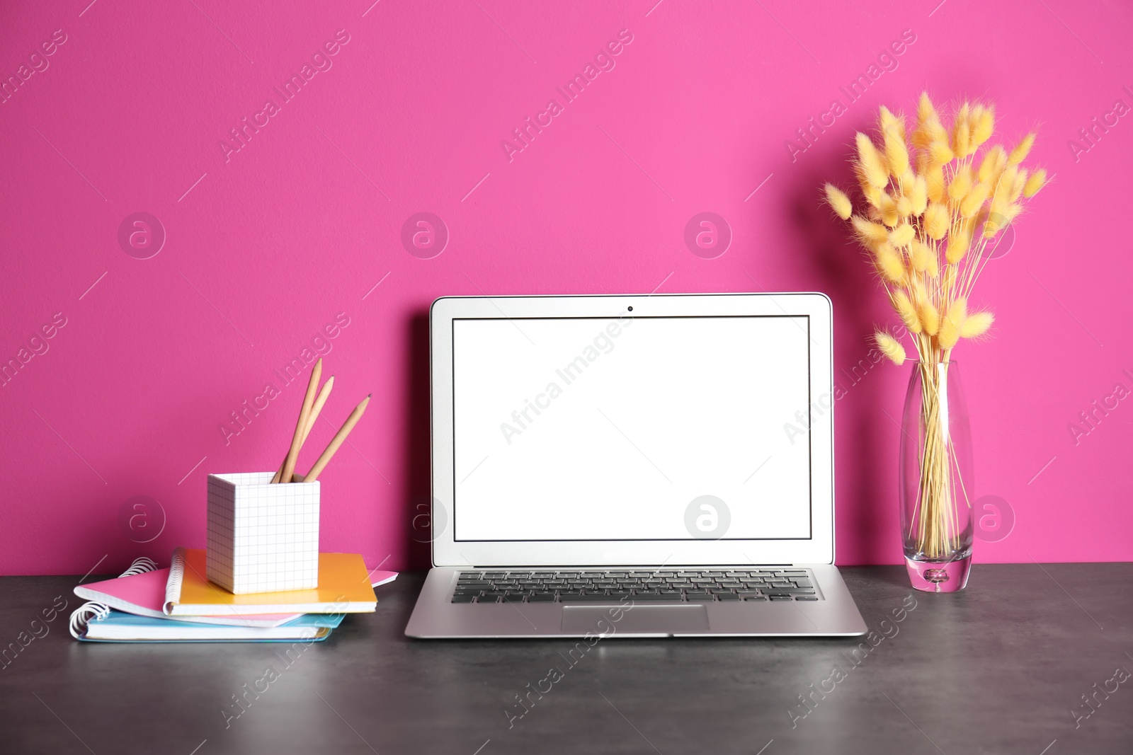 Photo of Modern laptop monitor on table against color wall. Mock up with space for text