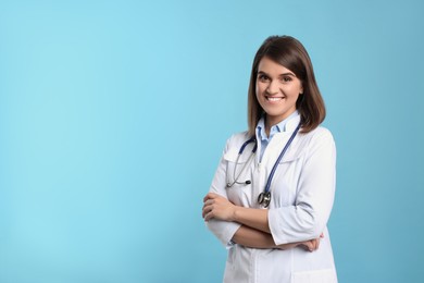 Pediatrician with stethoscope on light blue background, space for text