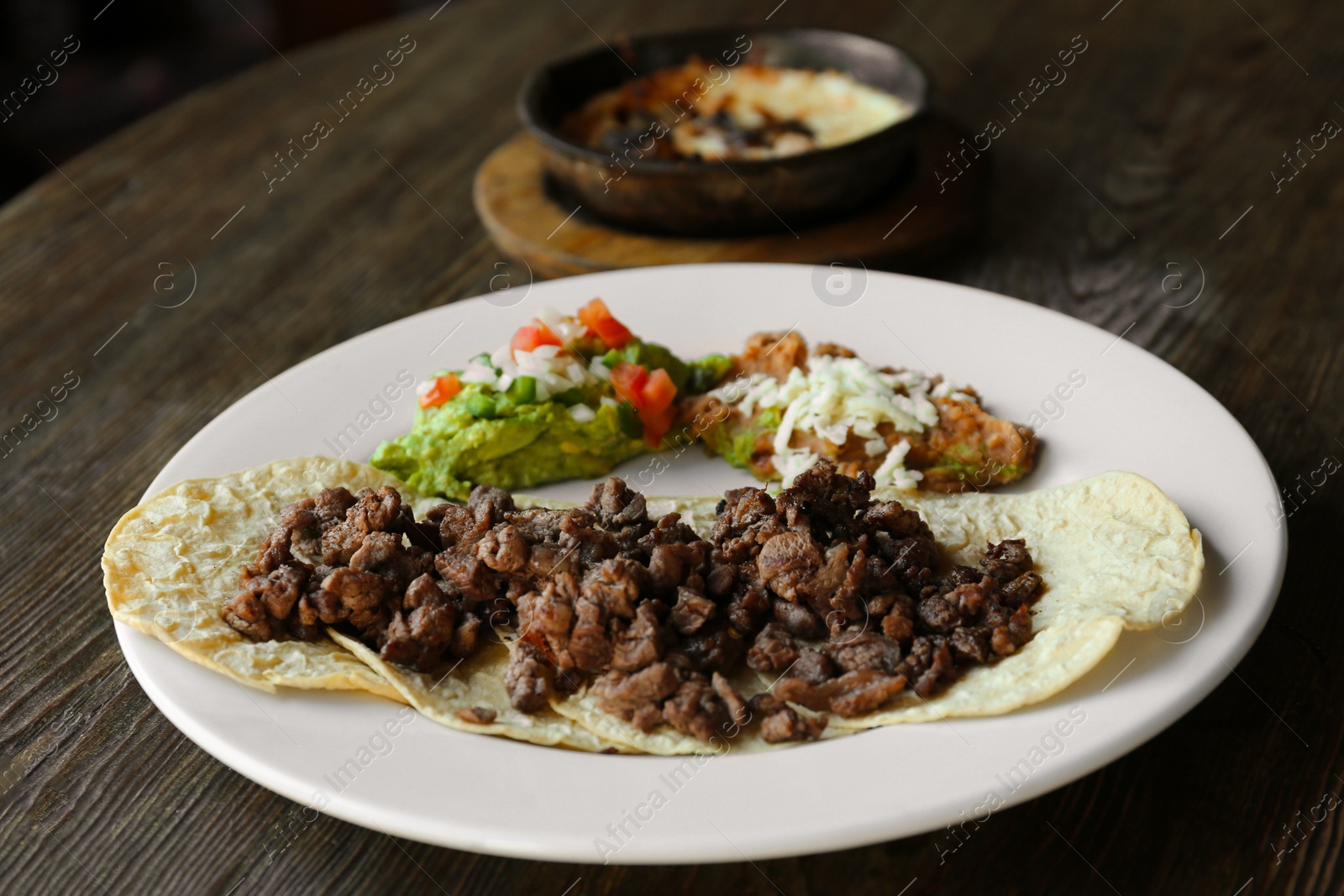 Photo of Plate with delicious tacos served on wooden table