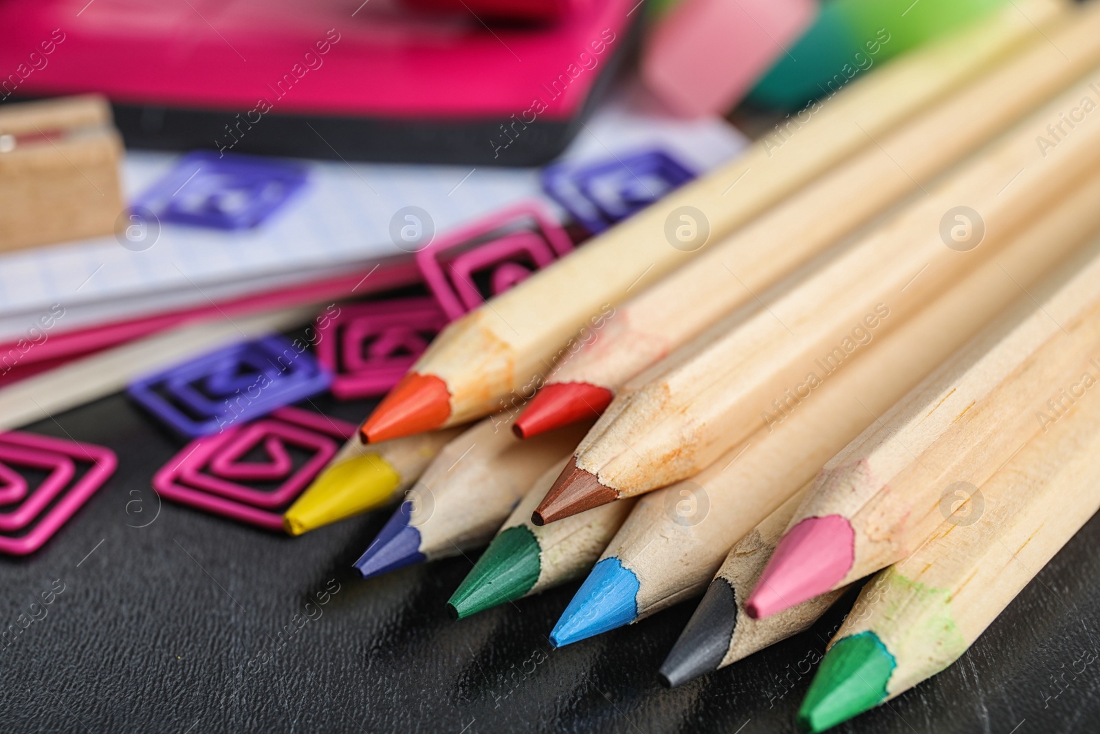 Photo of Different colorful stationery on chalkboard surface. Back to school