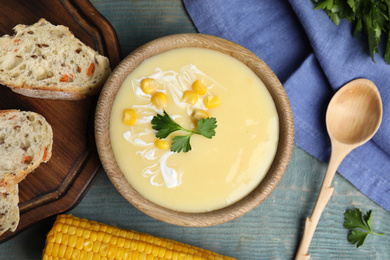 Photo of Delicious corn cream soup served on light blue wooden table, flat lay