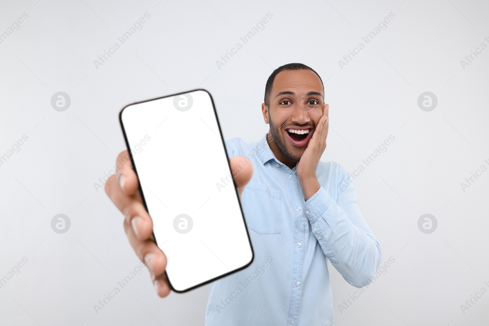 Photo of Surprised man showing smartphone in hand on white background