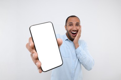 Surprised man showing smartphone in hand on white background