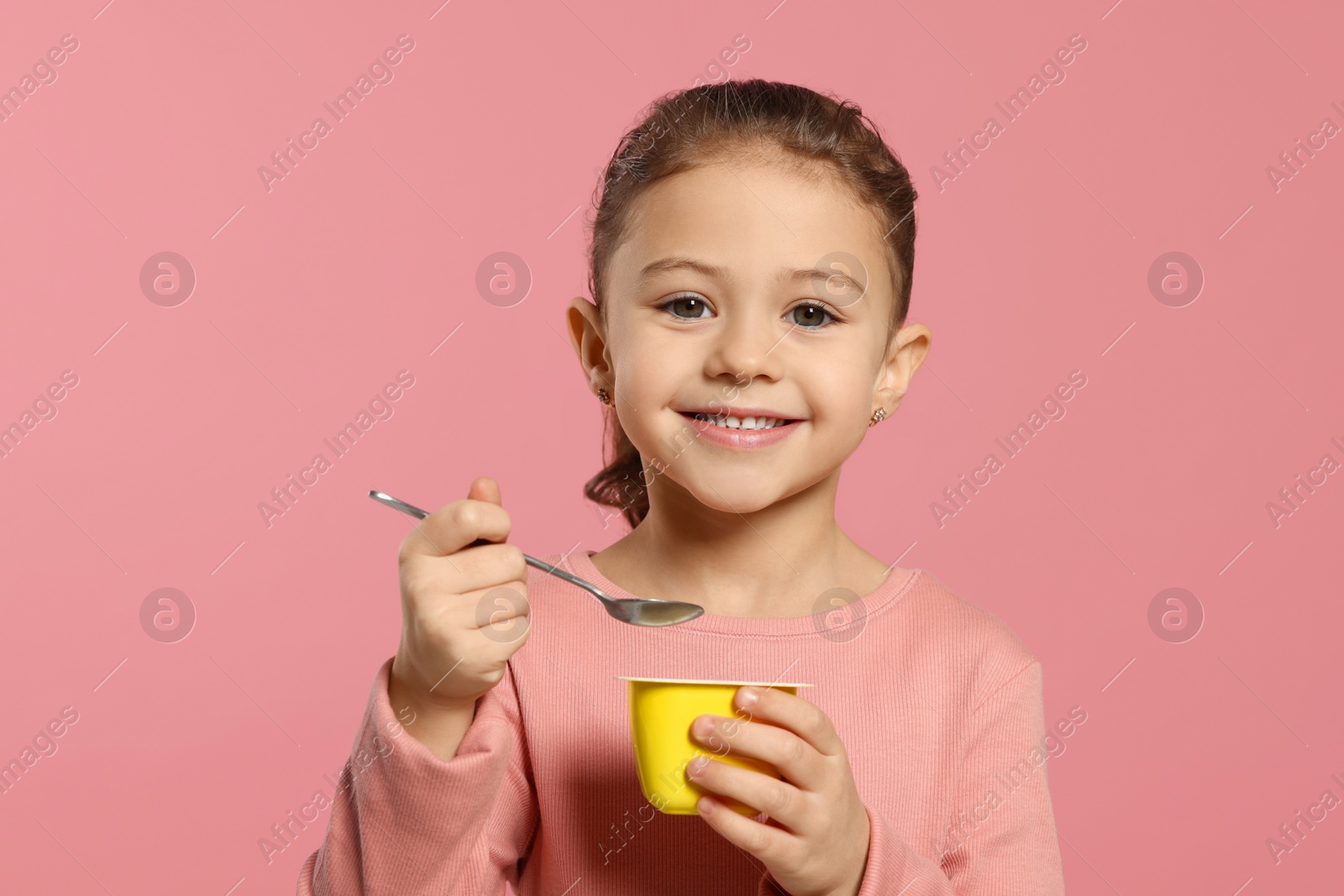 Photo of Girl with tasty yogurt on pink background