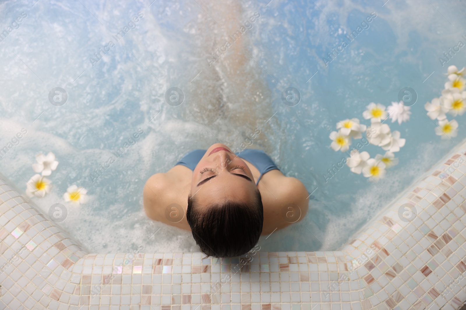 Photo of Beautiful woman relaxing in spa swimming pool, top view