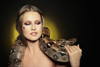Photo of Beautiful woman with boa constrictor on color background. Space for text