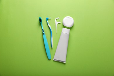Flat lay composition with dental floss and different teeth care products on green background