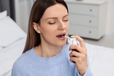 Photo of Adult woman using throat spray in bedroom