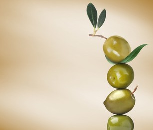 Stack of whole green olives with leaves on pastel gold gradient background, space for text