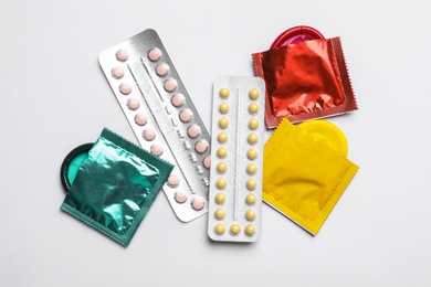 Photo of Condoms and birth control pills on white background, top view. Safe sex concept