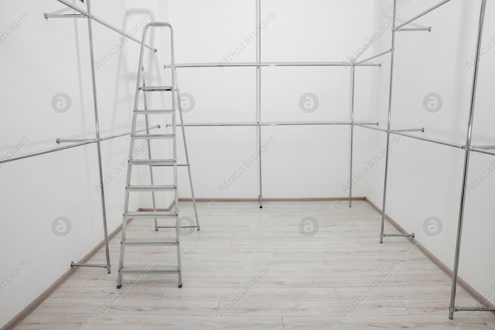 Photo of Ladder and metal pipes in empty renovated room