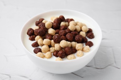 Photo of Breakfast cereal. Tasty corn balls with milk in bowl on white textured table, closeup