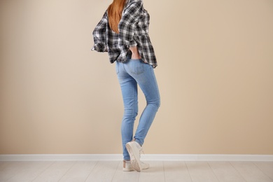 Photo of Young woman in stylish jeans near light wall