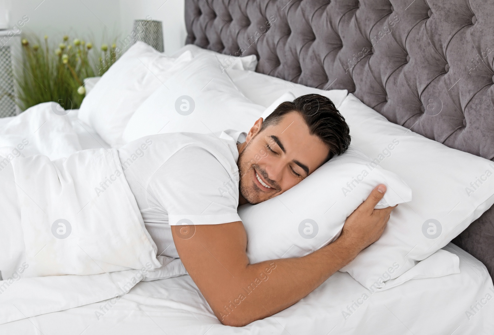 Photo of Young man sleeping in bed with soft pillows at home