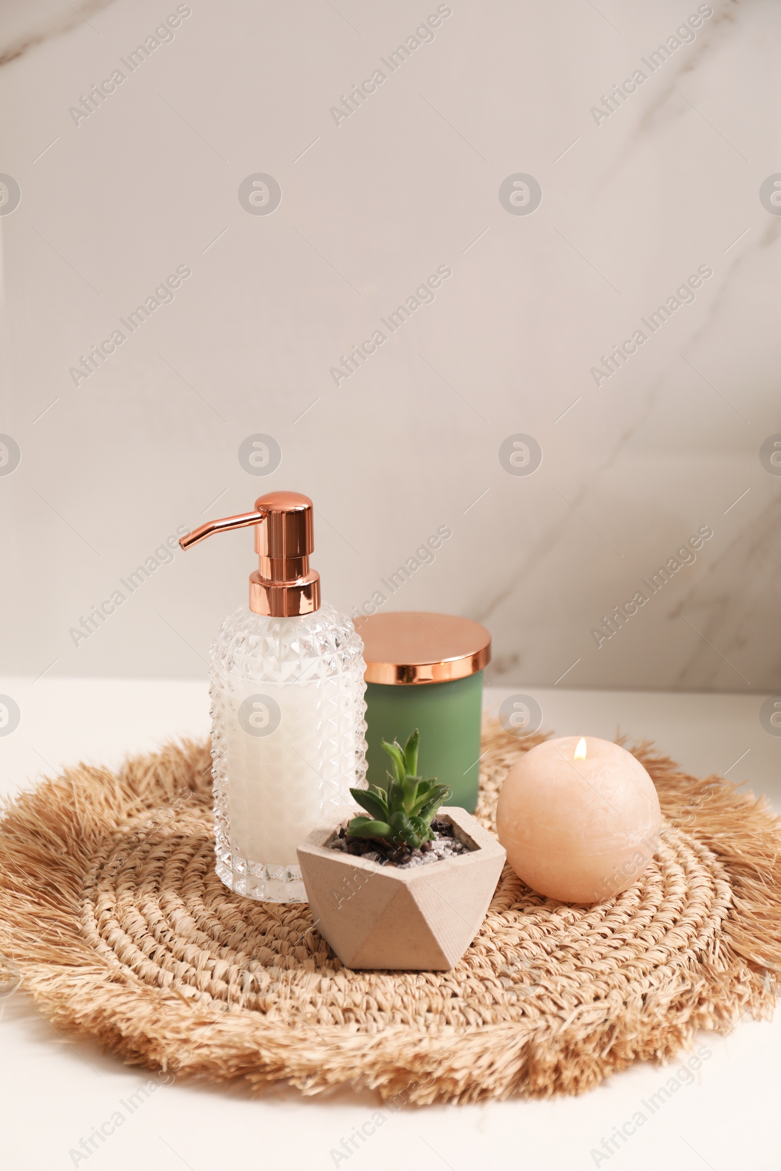 Photo of Soap dispenser, plant and burning candle on countertop in bathroom. Space for text