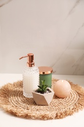 Photo of Soap dispenser, plant and burning candle on countertop in bathroom. Space for text