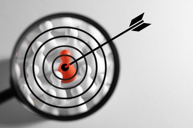 Arrow aiming to pawn, view through magnifying glass with target. White background