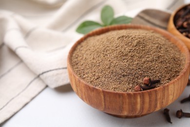 Photo of Aromatic clove powder and dried buds in bowls on white table, closeup. Space for text