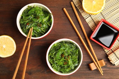 Photo of Japanese seaweed salad served on wooden table, flat lay
