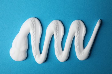 Photo of Sample of shaving foam on blue background, top view